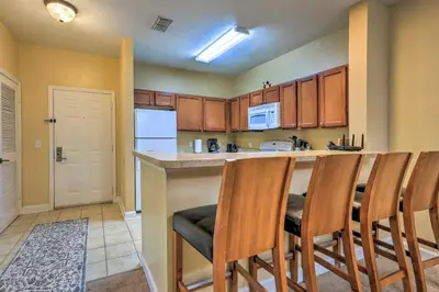 a kitchen with a bar with chairs and a refrigerator at Sun-Soaked Kissimmee Gem with Resort Amenities! in Kissimmee