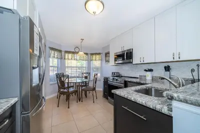 a kitchen with a table with chairs and a refrigerator at South Facing Pool with Stunning Lake View - Family Friendly Home - Nr Disney in Kissimmee