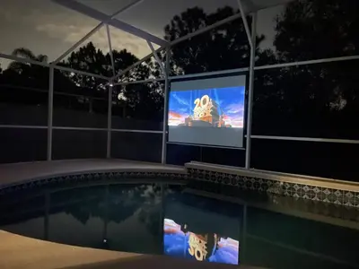 a swimming pool in front of a tv with a movie on it at 3 Bedroom Villa with Poolside Cinema and Games Room Close to theme Parks sleeps 6 in Orlando