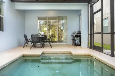 a patio with a pool and a table and chairs at Fun Family Villa Pool BBQ Near Disney World 5BR in Kissimmee