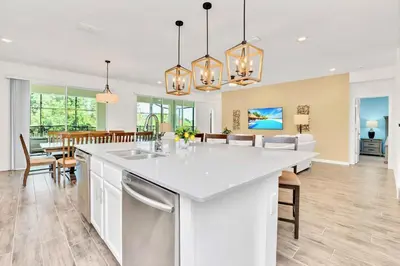 a kitchen and living room with a large white counter top at Upstay 9BR Disney Retreat w Pool, BBQ & Hot Tub in Kissimmee