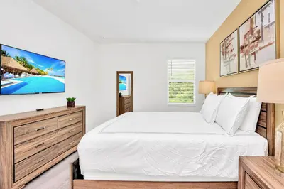 a bedroom with a white bed and a tv at Upstay 9BR Disney Retreat w Pool, BBQ & Hot Tub in Kissimmee
