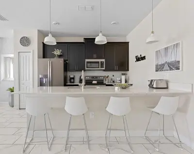 a kitchen with a large white counter and white stools at Disney Familly Lovers up to 11 SL4928 in Kissimmee