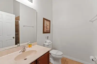 a bathroom with a sink and a toilet and a mirror at Ground floor spacious house 4BR VP2512 in Kissimmee