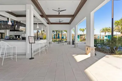 a patio with chairs and a bar with palm trees at 4 BR Bright Cozy at Storey Lake SL3113 in Kissimmee