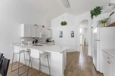 a white kitchen with a counter and stools at 4 BR No carpet Just Remodeled Unit SR1205 in Kissimmee