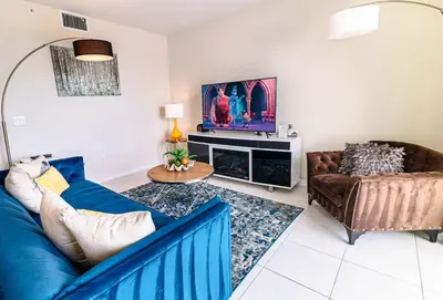 a living room with a blue couch and a tv at 2 BR Modern Apt near Disney SL4741 in Kissimmee