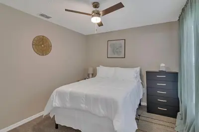 a bedroom with a white bed and a ceiling fan at Disney Themed House Free Heated Pool close Disney 5br 9bd in Orlando