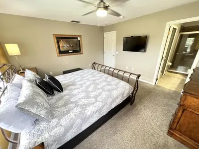 a bedroom with a bed and a flat screen tv at Mickeys Escape - Magical Lakeview 7BR - 4 Master Suites Pool & Hot Tub BBQ Home Theater and 2 Miles Disney! in Orlando