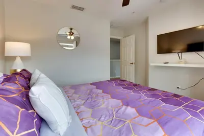 a bedroom with a bed with a purple comforter at 12 Mi to Disney Family Home with Resort Amenities! in Kissimmee