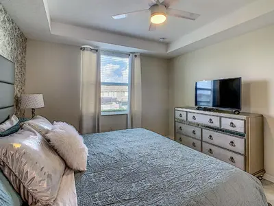 a bedroom with a bed and a flat screen tv at Luxury Brand NEW 2 bedroom apt near DISNEY! in Kissimmee