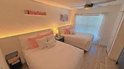 a bedroom with two beds and a window at Villas at Seven Dwarfs Resort - Near to Disney in Kissimmee