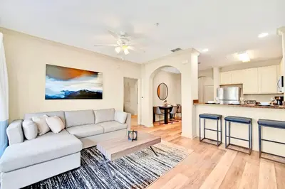 a living room with a couch and a kitchen at Near Disney - Spacious 3BR Condo with Pool in Orlando