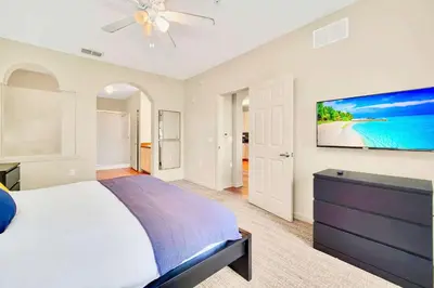 a bedroom with a bed and a tv on a wall at Near Disney - Spacious 3BR Condo with Pool in Orlando