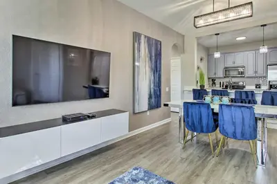 a kitchen and dining room with a large tv and blue chairs at Vista Cay Resort Condo about 5 Mi to Universal! in Orlando