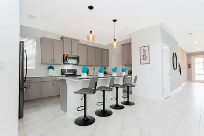 a kitchen with a bar with stools in it at Stunning Family Friendly 5 Bd w/ Pool Close to Disney @ Storey Lake 4242 in Kissimmee