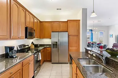 a kitchen with wooden cabinets and a stainless steel refrigerator at Vista Cay at Epic Universe - Luxury 4 bedroom penthouse in Orlando