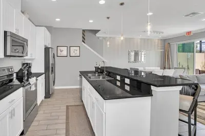 a kitchen with white cabinets and black counter tops at 4 Bed townhome with Private Pool Near Disney! townhouse in Kissimmee