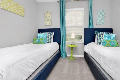 two beds in a room with blue curtains at 4 Bed townhome with Private Pool Near Disney! townhouse in Kissimmee