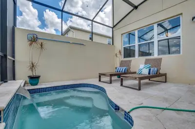 a swimming pool in the middle of a patio with two benches at 4 Bed townhome with Private Pool Near Disney! townhouse in Kissimmee