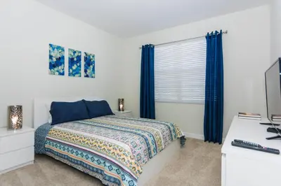 a bedroom with a bed and a window with blue curtains at Enchanting Decor Home with private pool in Kissimmee