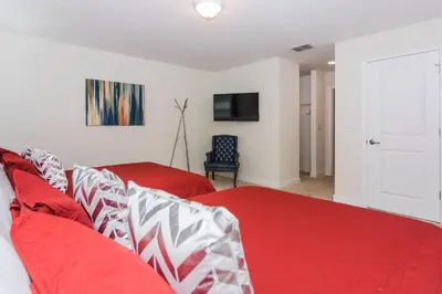a bedroom with two red beds and a tv at Enchanting Decor Home with private pool in Kissimmee