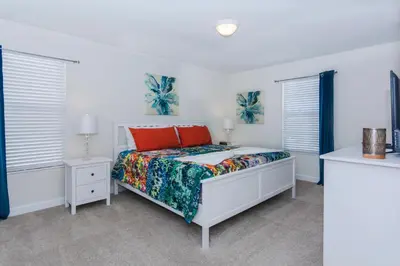 a white bedroom with a bed and two windows at Enchanting Decor Home with private pool in Kissimmee