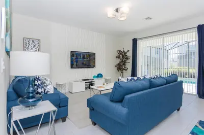 a living room with blue furniture and a large window at Enchanting Decor Home with private pool in Kissimmee