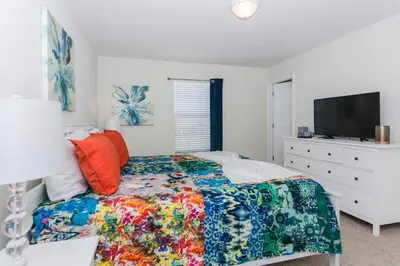a bedroom with a bed and a dresser with a tv at Enchanting Decor Home with private pool in Kissimmee