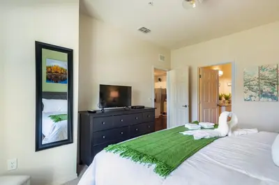 a bedroom with a large white bed with a television at Super Comfy and Spacious 3 Bedroom 15-20 minutes from Disney, with major shopping 4 minutes away in Kissimmee