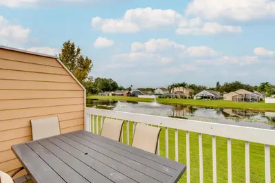 a wooden table and chairs on a balcony with a body of water at Kissimmee Condo with Private Porch Less Than 7 Mi to Disney! in Kissimmee