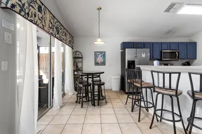 a kitchen with blue cabinets and bar stools at Family Oasis 5BR Villa with South Facing Pool and Games Room Near Disney in Kissimmee