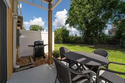 a patio with a table and chairs and a grill at JC DISNEY House in Kissimmee
