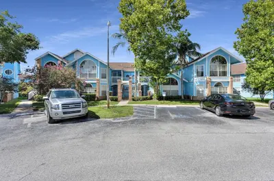 a blue house with cars parked in a parking lot at Poinciana Paradise in Kissimmee