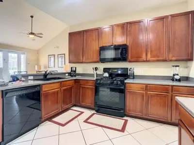 a kitchen with wooden cabinets and a black stove top oven at Fantastic 7 Bed 6 Bath in Prestigious Gated Comm, villa in Orlando