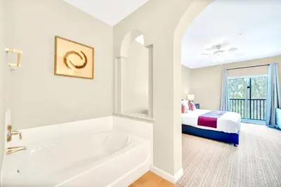 a white bathroom with a tub and a bed at 3BR Condo with Pool - Near Disney in Orlando