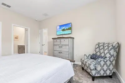 a bedroom with a bed and a chair and a tv at Delight Indoor Adventure Steps From Disney in Kissimmee