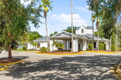 a white house with palm trees in the driveway at Baymont by Wyndham Orlando Lake Buena Vista South in Kissimmee