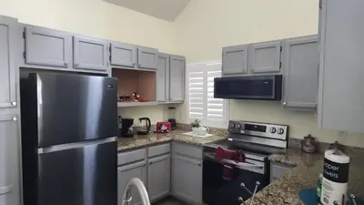 a kitchen with a stainless steel refrigerator and white cabinets at My Home in Orlando in Kissimmee