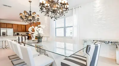 a dining room with a glass table and white chairs at Elegant Fun Vacation Home at Encore Resort 7529 in Orlando