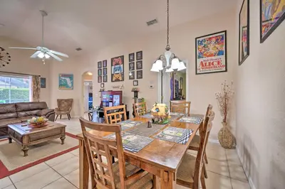 a dining room and living room with a table and chairs at 10 Mi to Disney and Heated Pool Florida Abode! in Orlando