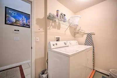 a laundry room with a washing machine and a tv at 10 Mi to Disney and Heated Pool Florida Abode! in Orlando