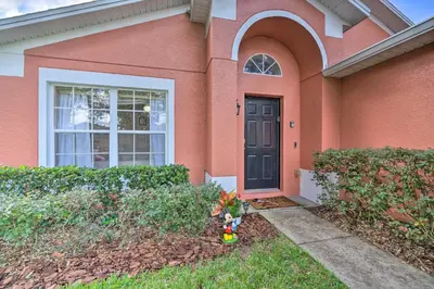 a pink house with a black door and a yard at 10 Mi to Disney and Heated Pool Florida Abode! in Orlando