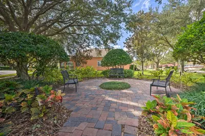a brick patio with two chairs and trees at 10 Mi to Disney and Heated Pool Florida Abode! in Orlando
