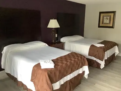 a hotel room with two beds and a lamp at Heritage Park Inn in Kissimmee