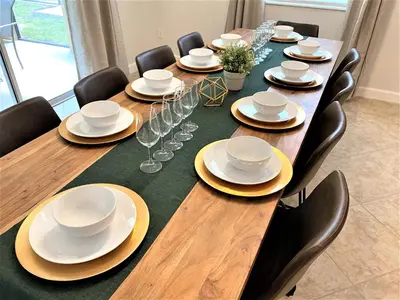a long table with chairs and plates and wine glasses at Marvelous Magical House: Amazing Themes and Pool, 5mi Disney in Kissimmee