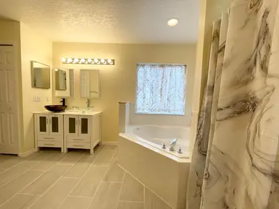 a bathroom with a bath tub and a sink at Fully Renovated, Quiet, Spacious Disney Themed Pool Home with Office in Kissimmee