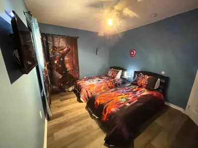 a bedroom with two beds and a painting on the wall at Fully Renovated, Quiet, Spacious Disney Themed Pool Home with Office in Kissimmee
