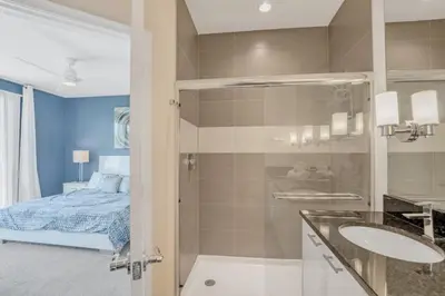 a bathroom with a shower and two sinks and a bed at 1511RETREAT townhouse in Orlando