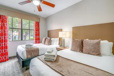 two beds in a hotel room with red curtains at Disney Good Neighbor Resort Condo Less Than 4 Mi to WDW! in Orlando